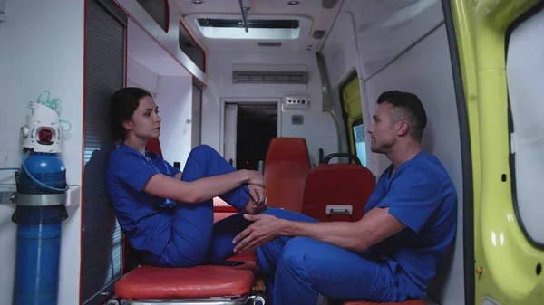 Corpseman con la enfermera se sienta en el coche de la ambulancia, habla y ríe . — Foto de Stock