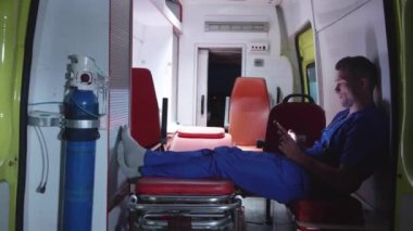 Üniformalı corpsman ambulans arabada strecher üzerinde oturup.