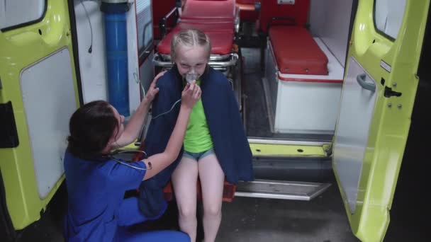 Chica sentarse un coche ambulancia con máscara de oxígeno . — Vídeo de stock