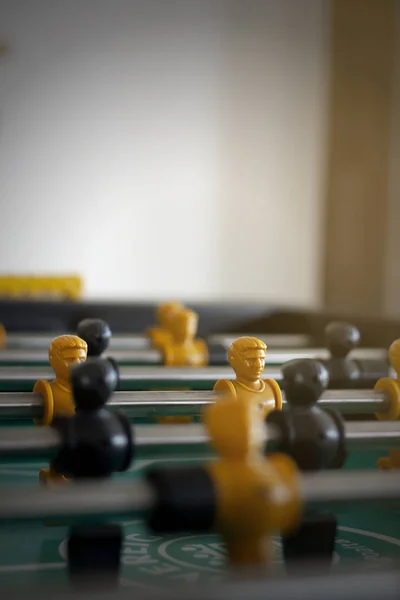 The table football game closeup.Foosball table game.Soccer game is a plastic player with yellow and black colors, There is a metal to hold the core.