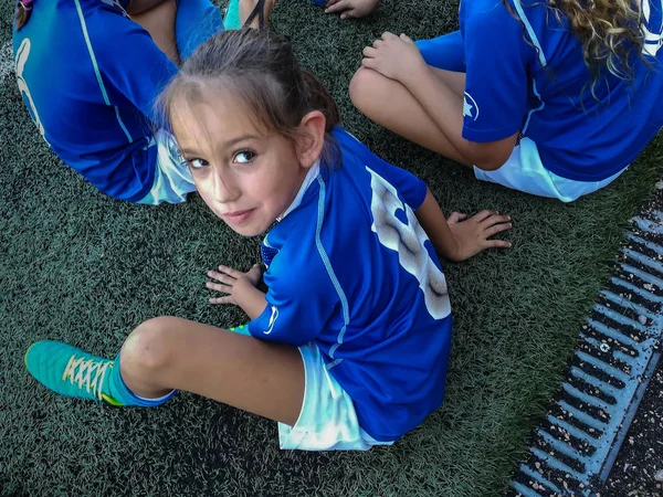 Little football girl sitting on grass