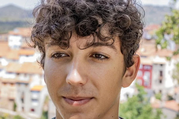 Arka planda eski bir dağ köyü ile genç adam Portresi