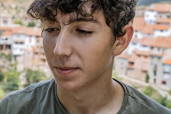 Arka planda eski bir dağ köyü ile genç adam Portresi