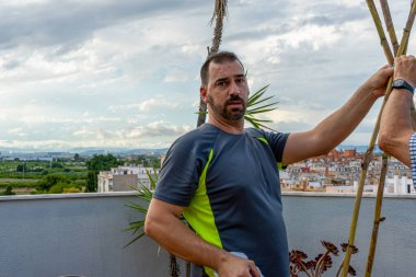 Sakallı adam bitkileri yönetmek için şehir bahçesini kamış ve iplerle düzeltiyor. Sağlıklı yaşam konsepti