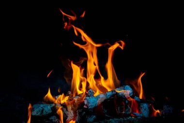 Alevler, turuncu ağaç gövdeleri ve siyah arka planla yapılan şenlik ateşinin farklı şekillerinde. Huzur kavramı