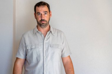 Bej arka planda bej gömlekli endişeli sakallı adamın portresi. Endişe kavramı