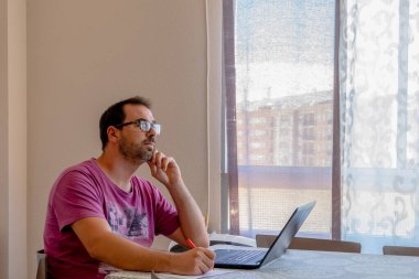 Mor tişört giymiş sakallı adam dizüstü bilgisayara bakıyor. endişe kavramı