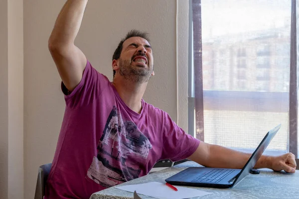 忧心忡忡的大胡子男人穿着紫色的T恤 看着笔记本电脑 忧虑的概念 — 图库照片