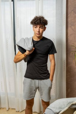 Beyaz perde arkasında siyah tişört giyen kıvırcık saçlı çekici genç adam. Moda konsepti