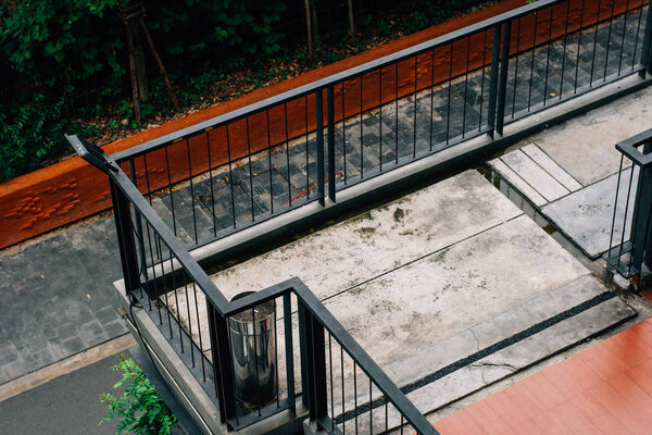Concrete balcony with black metal railing and the stainless ashtray bin.