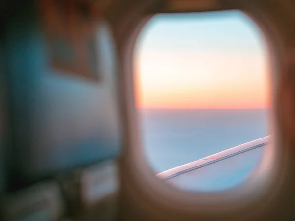 Looking out to the sky horizon and enjoying beautiful sunrise through the plane window. The beginning of a new journey concept. Beautiful wallpaper with copy space.