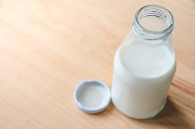 Ahşap yüzeyde şapka olan bir süt şişesi. Sağlıklı bir içki konsepti. Kopya Uzay duvar kağıdı. 