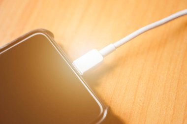 Ahşap masada şarj yakın çekim siyah renkli cep telefonu akıllı telefon.