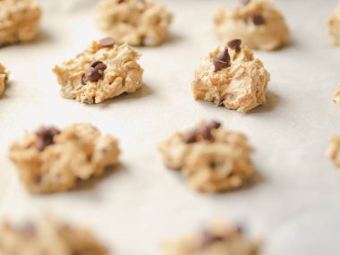 Siyah bir fırın tepsisinde balmumu kağıt üzerinde Çiğ çikolata cips çerez hamur.