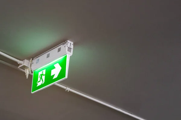 Emergency exit sign with right arrow in department store underground car parking. Safety first concept. Copy space wallpaper.