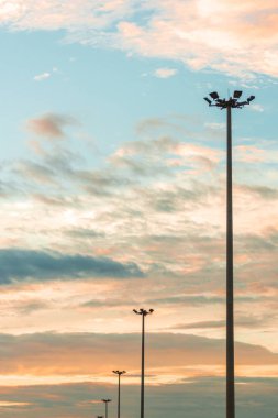 Mavi gökyüzüne ve gün batımında bulutlara karşı otoyol ışığı direği.