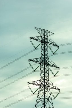 Gün batımında mavi gökyüzüne karşı yüksek güçlü elektrik direği.