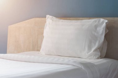 Sabahları otel odasında beyaz çarşaflı yumuşak bir yastık. Çatı katı tarzı otel iç tasarımı.