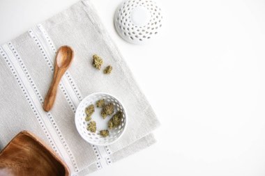 Esrar tomurcukları bir porselen kase üzerinde tahta kaşık, kase ve kapak yukarıdan aşağıya görünümü - Minimalist esrar ile gümüş bir Amerikan Servisi