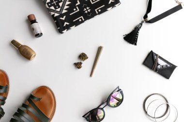 Esrar Eklem ve püskül boğan, sandalet, kedi gözü güneş gözlüğü, bilezik ve bir festival çantası ve ot çantası ile beyaz bir arka plan üzerinde tomurcukları.