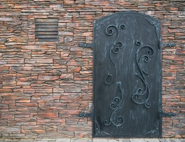 Puerta de hierro vieja con una pared de piedra — Foto de Stock