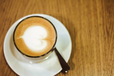 Kafe ve Restoran, kalp şekli latte sanat latte fincan beyaz tabak, ahşap masa üzerinde sıcak kahve kapatın. Kahve Cafe arka plan üzerinde yukarıdan Gıda için kullanın ve konsept iç. Düz yatıyordu 