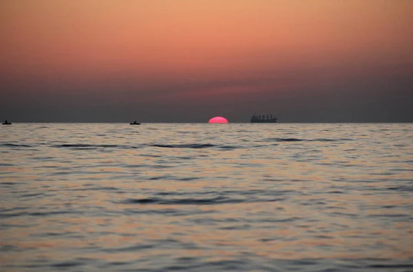 Gentle pink dawn over the sea with the pink sun and ship silhouettes on pink sun background