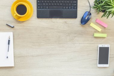 Dizüstü bilgisayar, sarf malzemeleri ve smartphone ile ofis resepsiyon masası. Üstten görünüm kopya alanı ile. Kahve fincanı ve bitki.