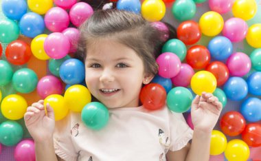 küçük gülümseyen kız oyun renkli yalan park Bahçesi topları.