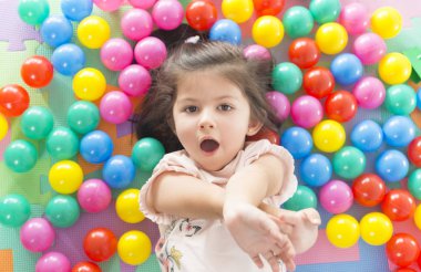 küçük gülümseyen kız oyun renkli yalan park Bahçesi topları.