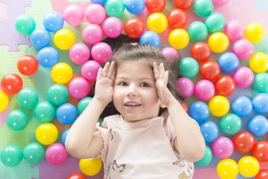 küçük gülümseyen kız oyun renkli yalan park Bahçesi topları.