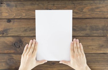 Ahşap arka planda boş kapaklı broşür tutan bir adam. Alay Et