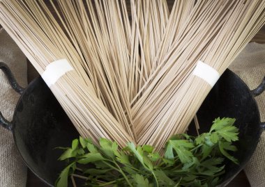 Siyah güveçte çiğ spagetti. Kara ahşap masada maydanozlu.