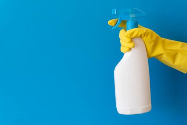 Sarı lastik eldiven, temiz sprey şişeyi mavi arka planda tutar. Temizlik servisi afişi. Temizlik ve temizlik konsepti. Düz yatıyordu.