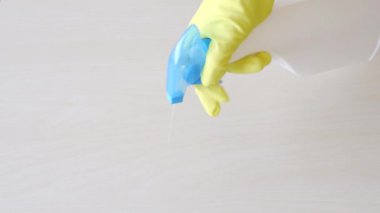 Ev masasını temizlemek mutfak masasının yüzeyini dezenfektan sprey şişesiyle dezenfekte etmek eldivenlerle yüzeyi yıkamak. COVID-19 önleme içeride dezenfekte ediliyor.