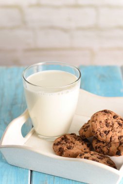 Beyaz tepside süt ve kurabiye. Turkuaz masada bisküvi