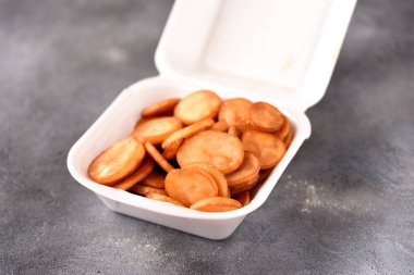 Gri bir arka planda plastik bir kutuda kızarmış patatesler doğranmış..