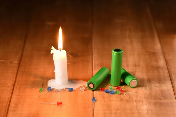 Burning candle, batteries and led bulb. Modern and medieval lighting.