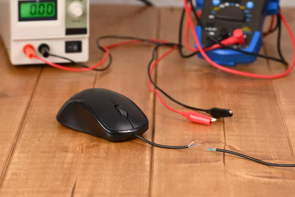 Broken mouse cord against the background of electronic measuring devices.