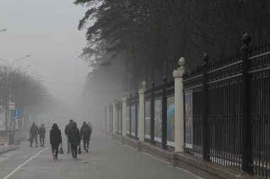 İnsanlar kaldırımda ağır siste yürümek. Bahar tezcan sırasında sis City.