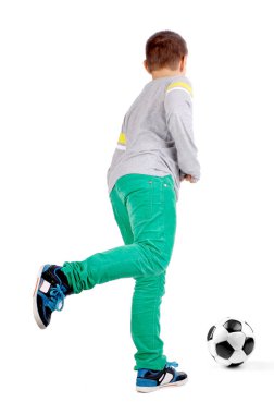 Beyazlar içinde futbol oynayan küçük çocuk.