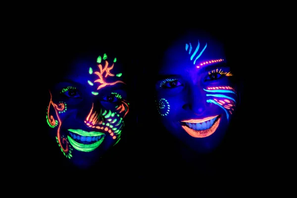 Young women with painted faces under UV light