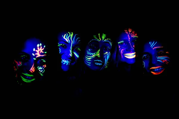 Young women with painted faces under UV light