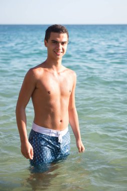 Genç sportif adam deniz kıyısında poz 