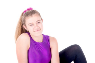 Genç jimnastikçi beyazlar içinde yalnız poz veriyor.