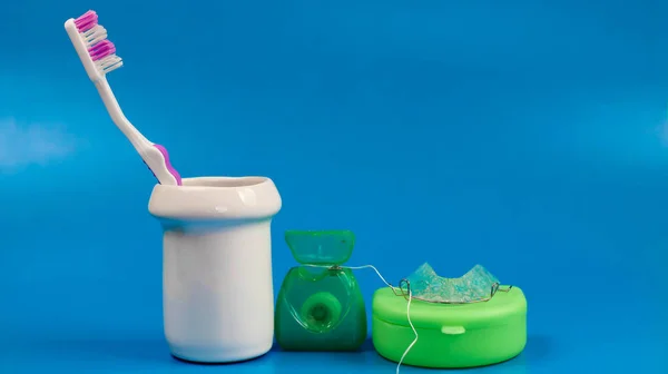 pink toothbrush with dental floss and dental retainer