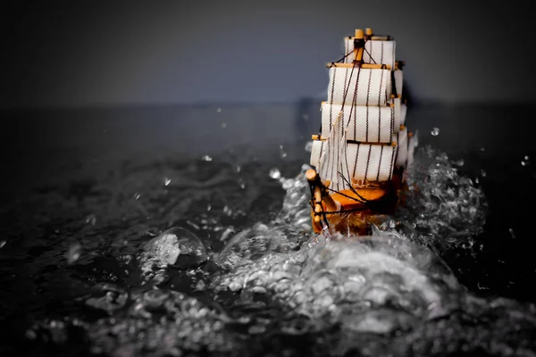 small toy boat in the water with big waves, black and white.