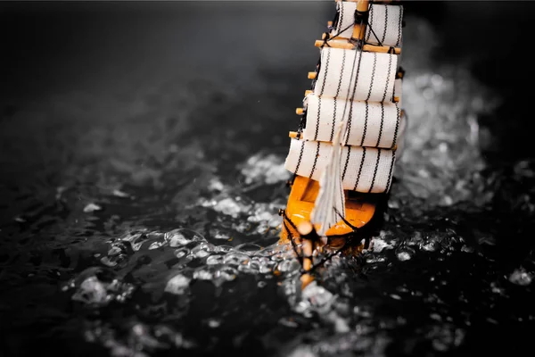 stock image small toy boat in the water with big waves, black and white.