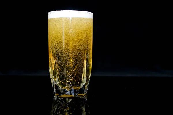glass with beer, black background, yellow beer.