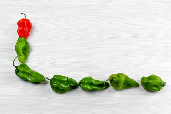 Small red and green peppers on white background